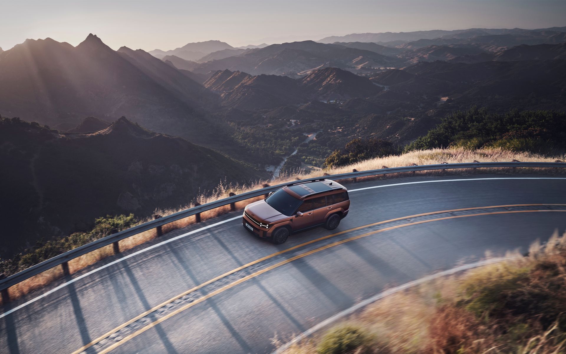 A car navigating a winding mountain road at sunset